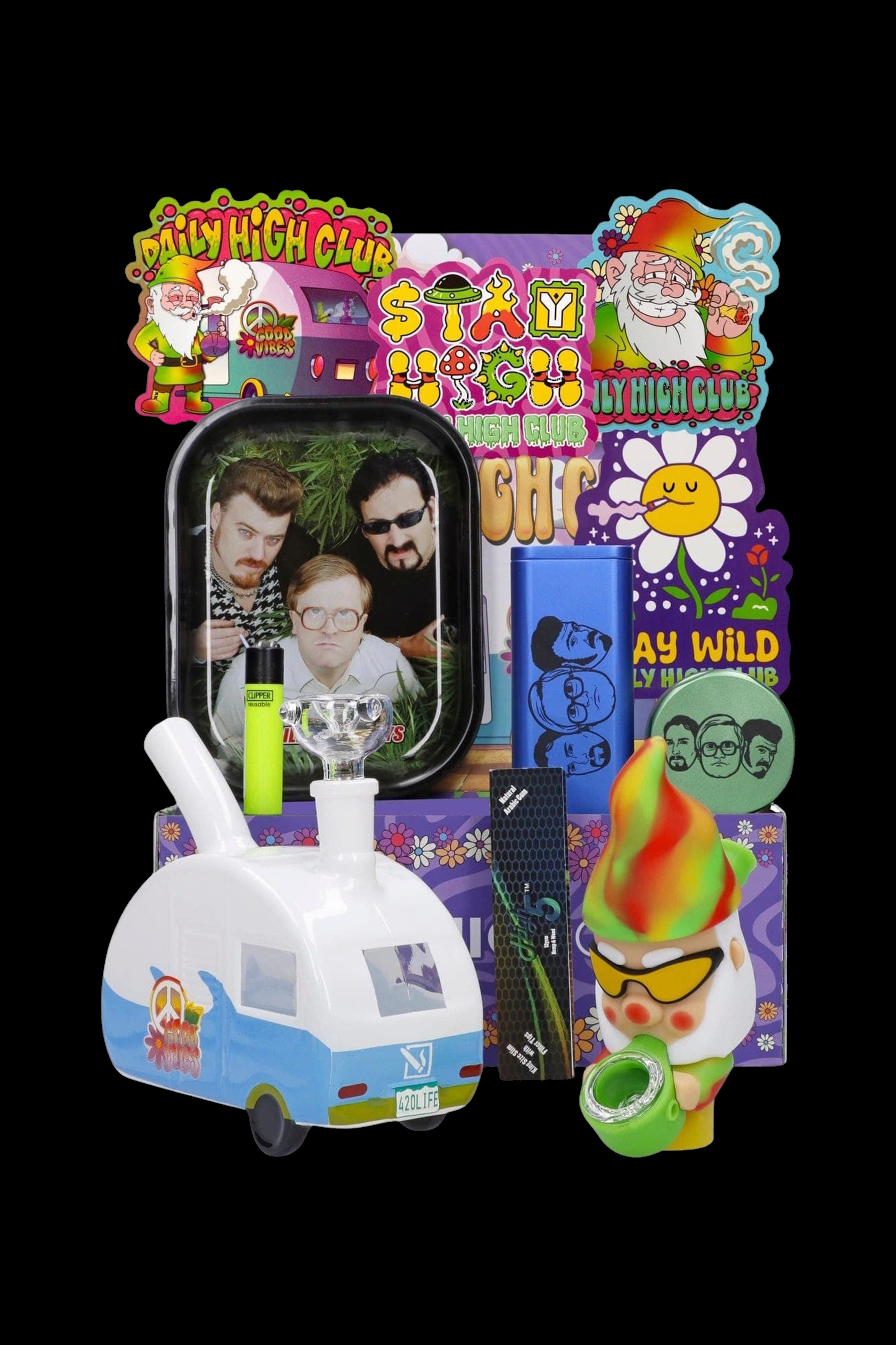 A colorful assortment of cannabis accessories including a rolling tray featuring portraits of Seth Rogen and Snoop Dogg, a glass water pipe shaped like a vintage Volkswagen van, a lighter, and various branded items with psychedelic designs.