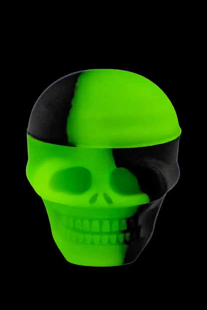 Glowing green and black skull-shaped silicone container.