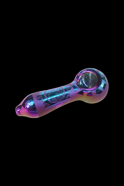 Iridescent glass pipe with etched designs against a black background.