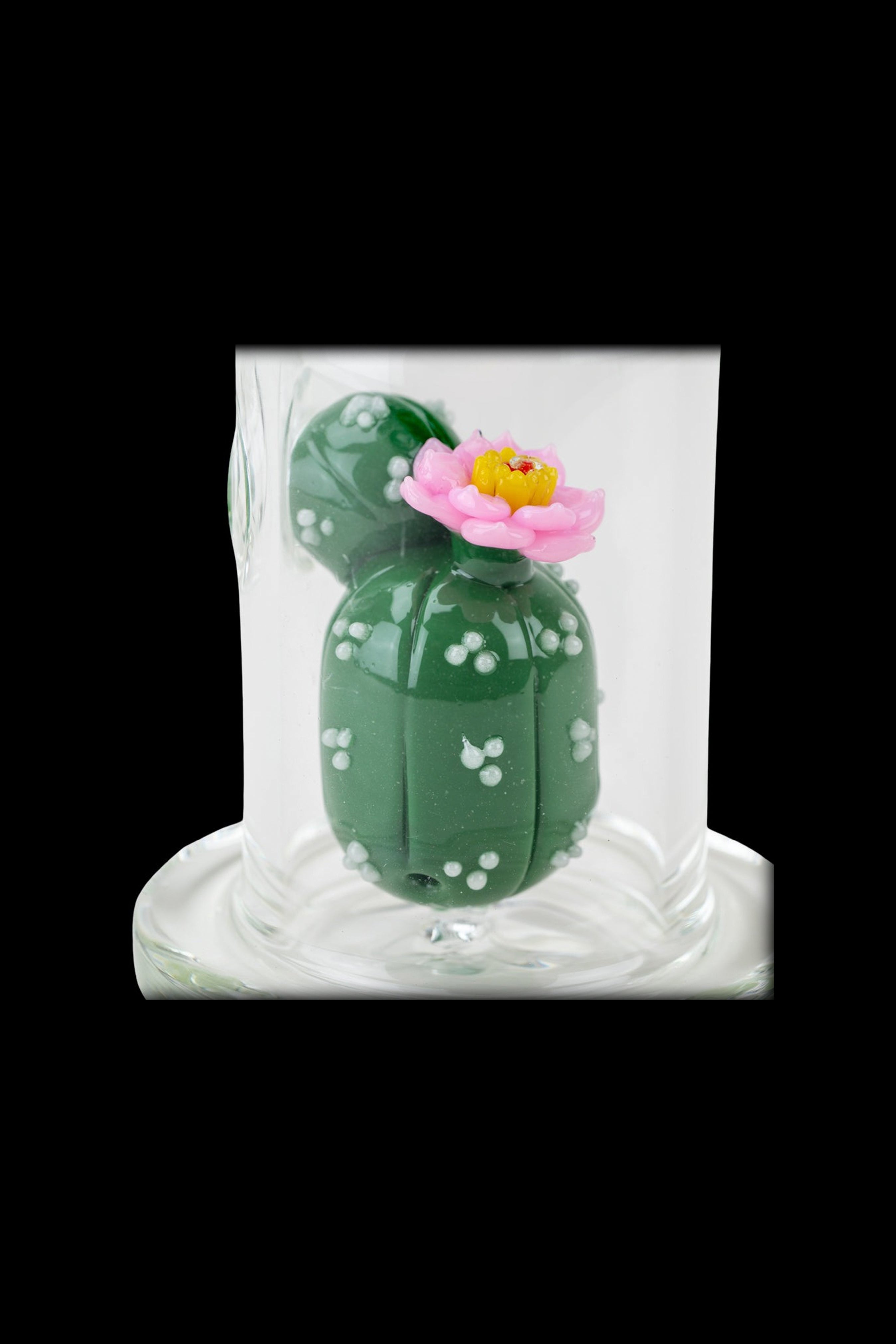 Green cactus-shaped cannabis container with a pink flower, sealed in plastic packaging.