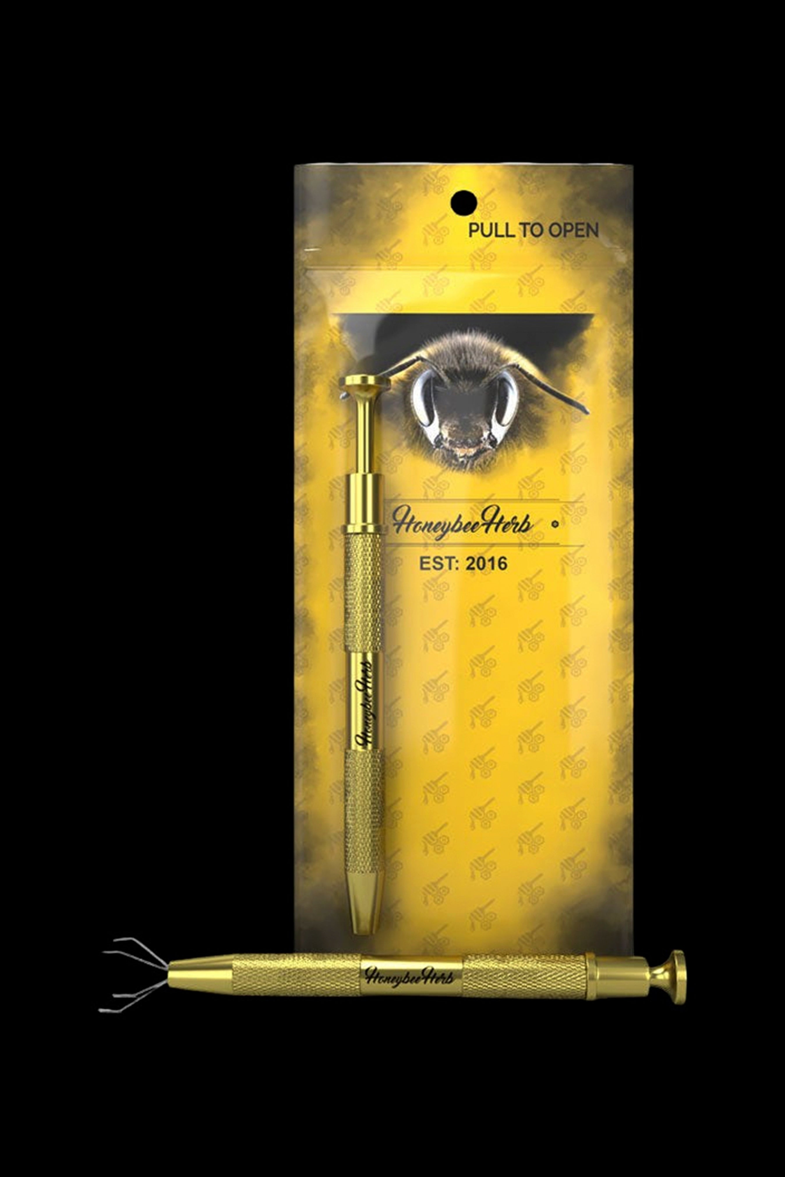 Gold cannabis dab tool with a bee-themed package labeled "Honeybee Herb EST. 2016."