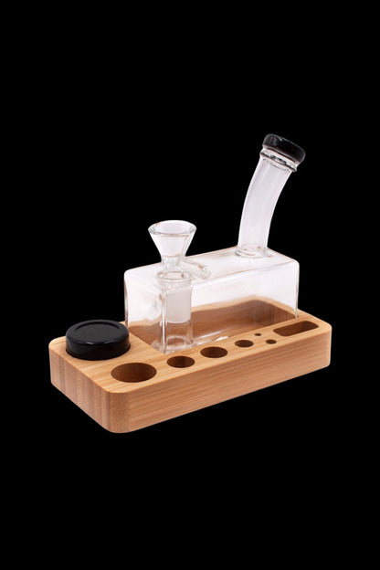 Glass bubbler and wooden organizer for cannabis accessories on a black background.