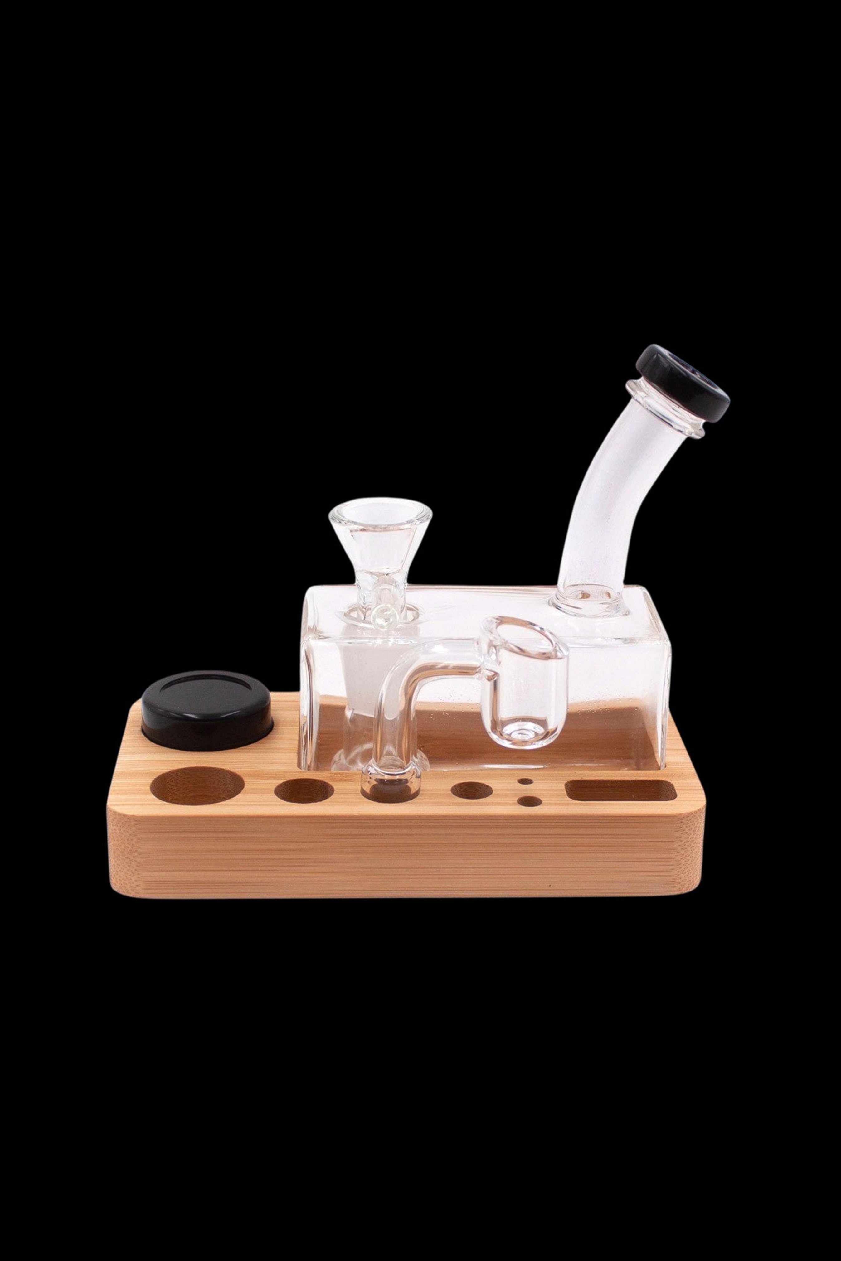 Clear glass dab rig with wooden base and accessories.