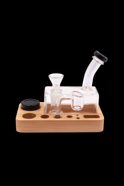 Clear glass dab rig with wooden base and accessories.