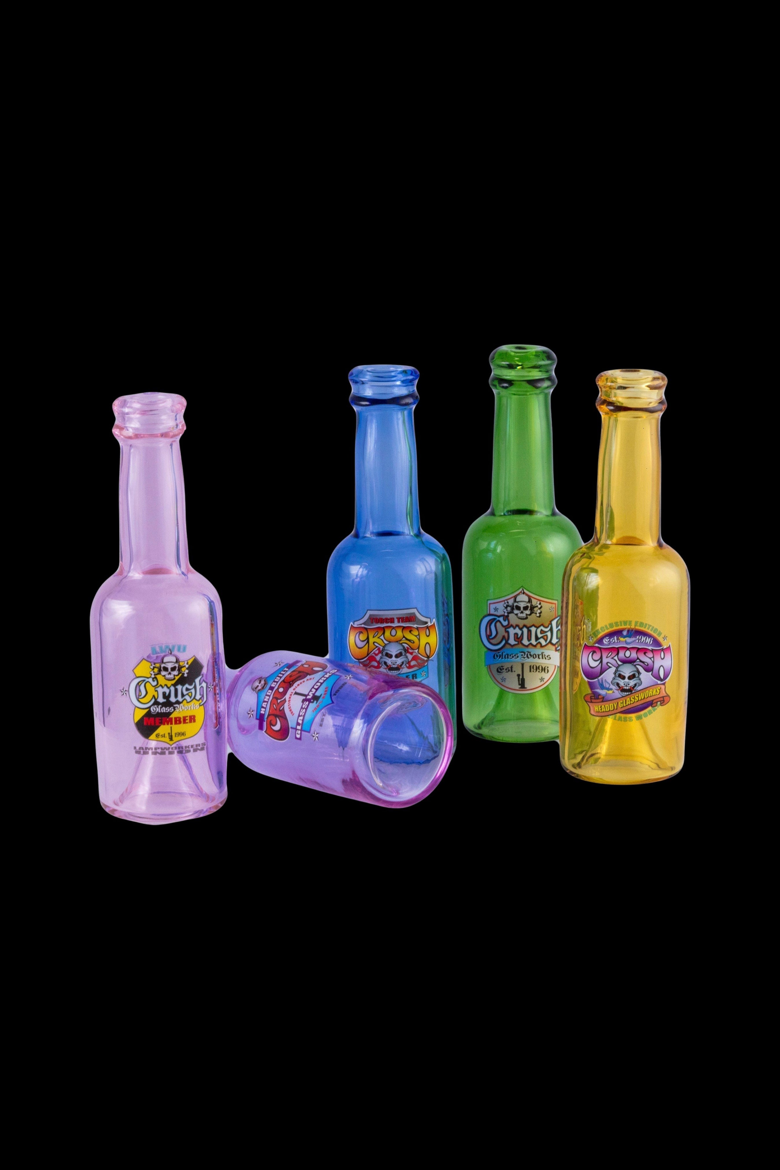 Colorful glass oil bottles and a shot glass with cannabis-themed branding against a black background.