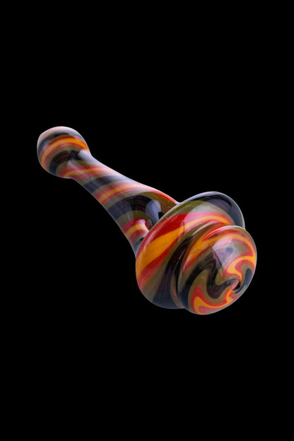 Hand-blown glass cannabis oil rig with red, orange, and black swirls against a black background.