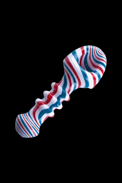 Red, white, and blue glass pipe isolated on a black background.