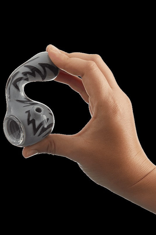 Hand holding a glass cannabis pipe with black swirl designs.