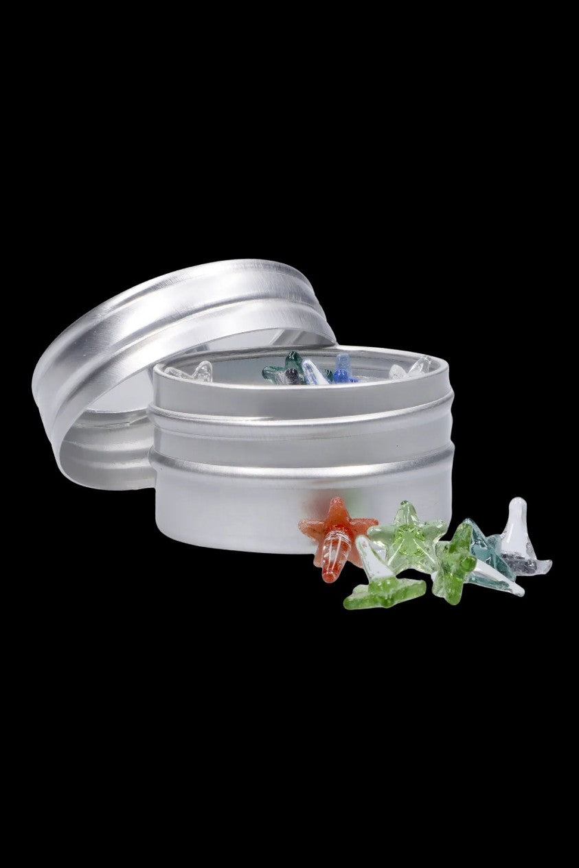 A close-up of the Famous X Glass Screens - 12 Pack, showing the colorful glass screens scattered on a reflective silver surface.