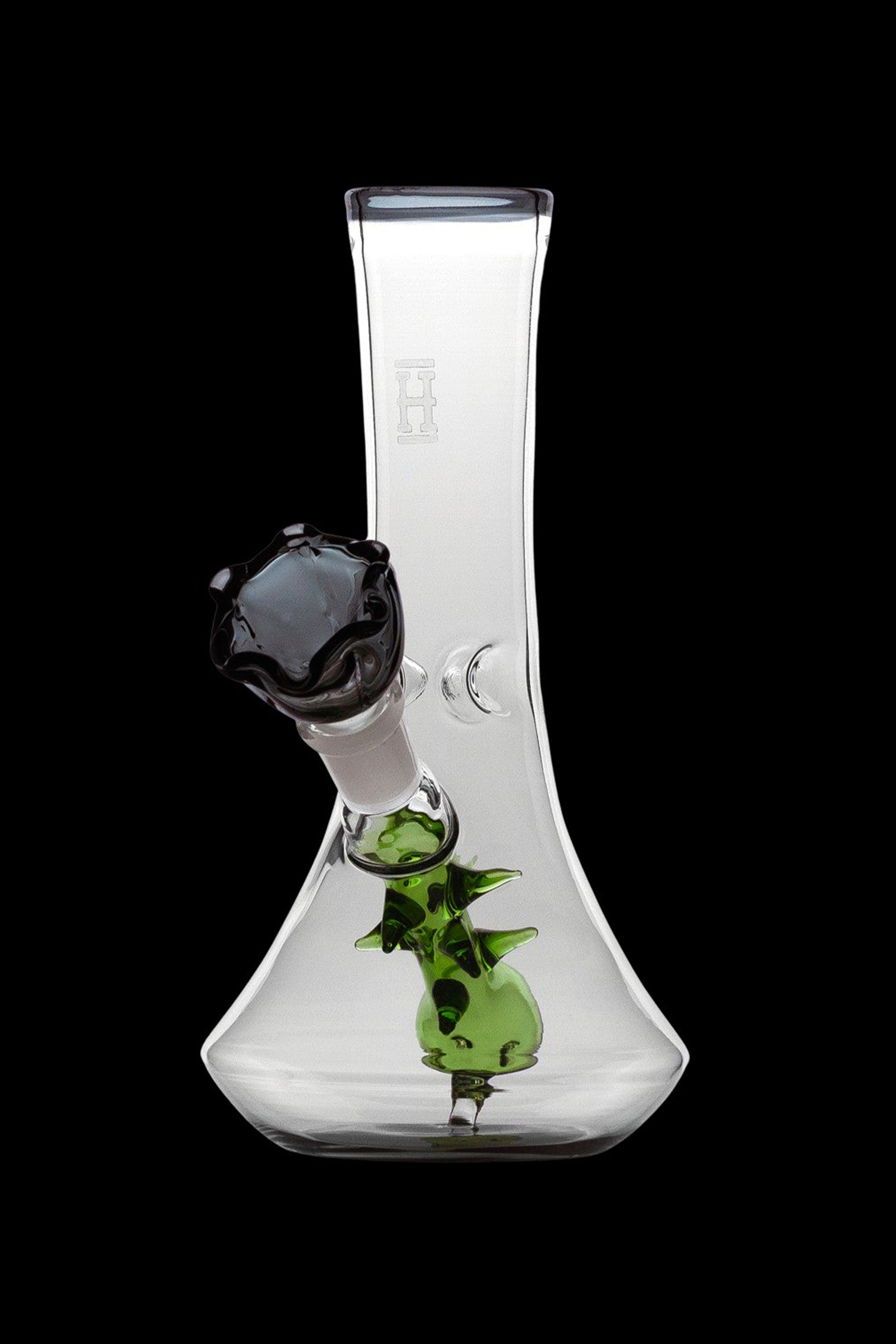Clear glass bong with green sculpted accents and a black mouthpiece, isolated on a black background.