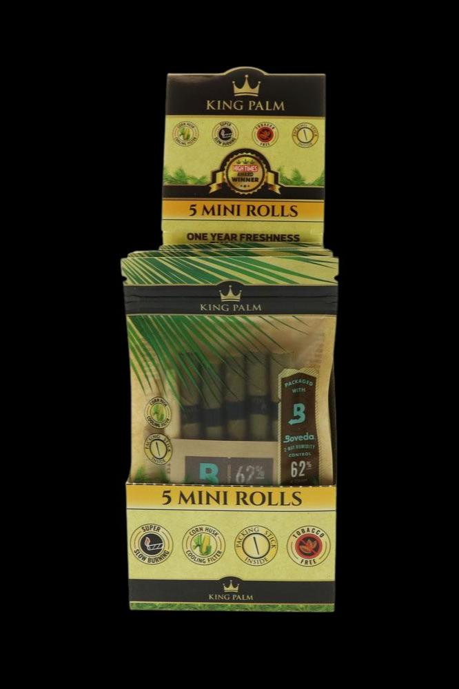 Stacked boxes of King Palm mini rolling papers with various seals indicating features like slow burning and corn husk filters.