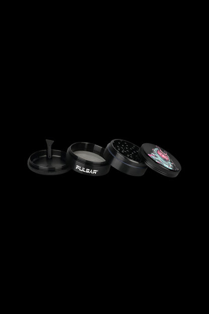Black metal grinder with four parts, including a floral-patterned top piece.