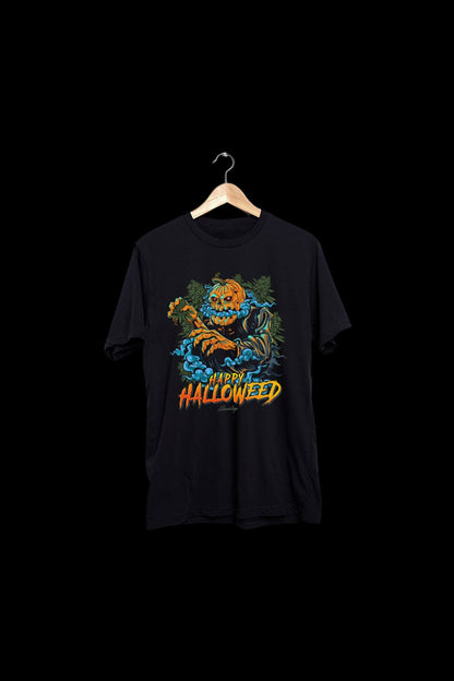 Black t-shirt with a vibrant orange and yellow "Happy Halloweed" graphic featuring a jack-o'-lantern skull and cannabis leaves, hanging on a wooden hanger against a black background.