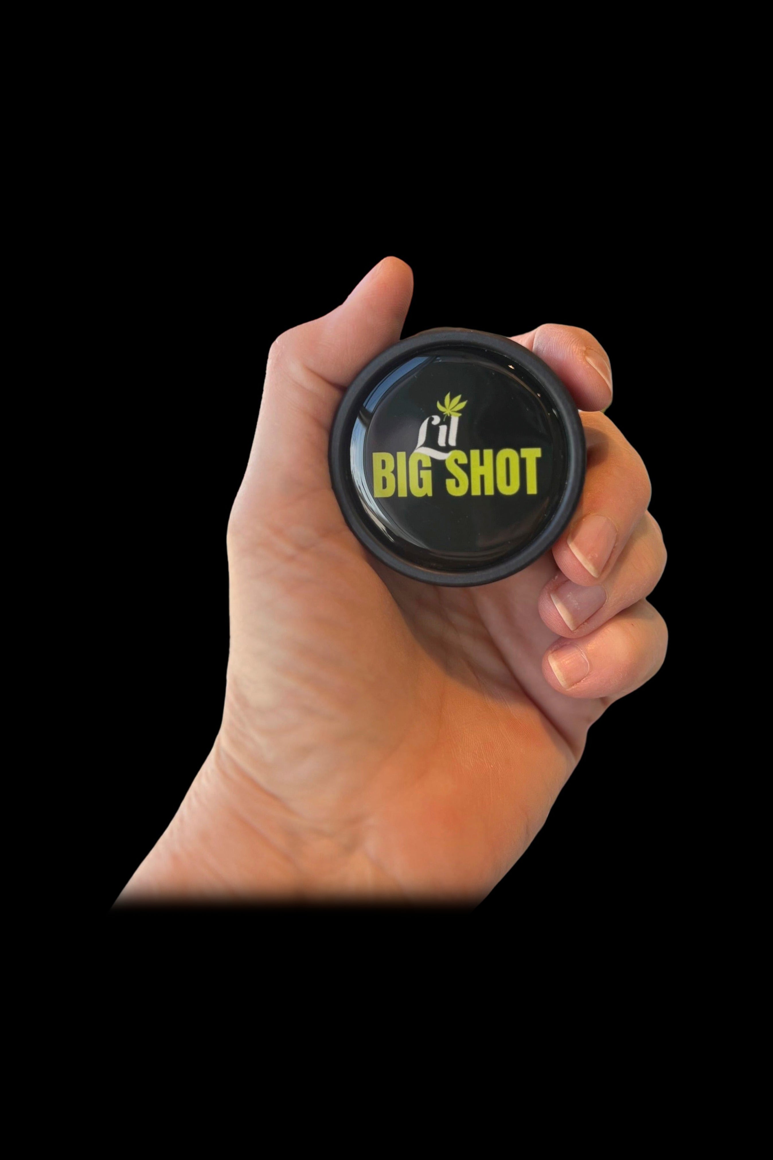 A hand holding a black jar labeled “Lil Big Shot” with a cannabis leaf design.