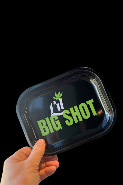 Hand holding a glossy black rolling tray with a green cannabis leaf and the text “LIT BIG SHOT.”