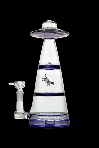 Clear glass water pipe shaped like a UFO with a cowboy riding a bucking bronco silhouetted within the water chamber, against a dark background.