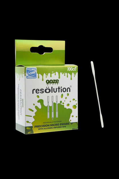 Angled close-up of the green-and-white box of Ooze Resolution Alcohol Micro Swabs – 100ct with one white swab shown vertically to the right