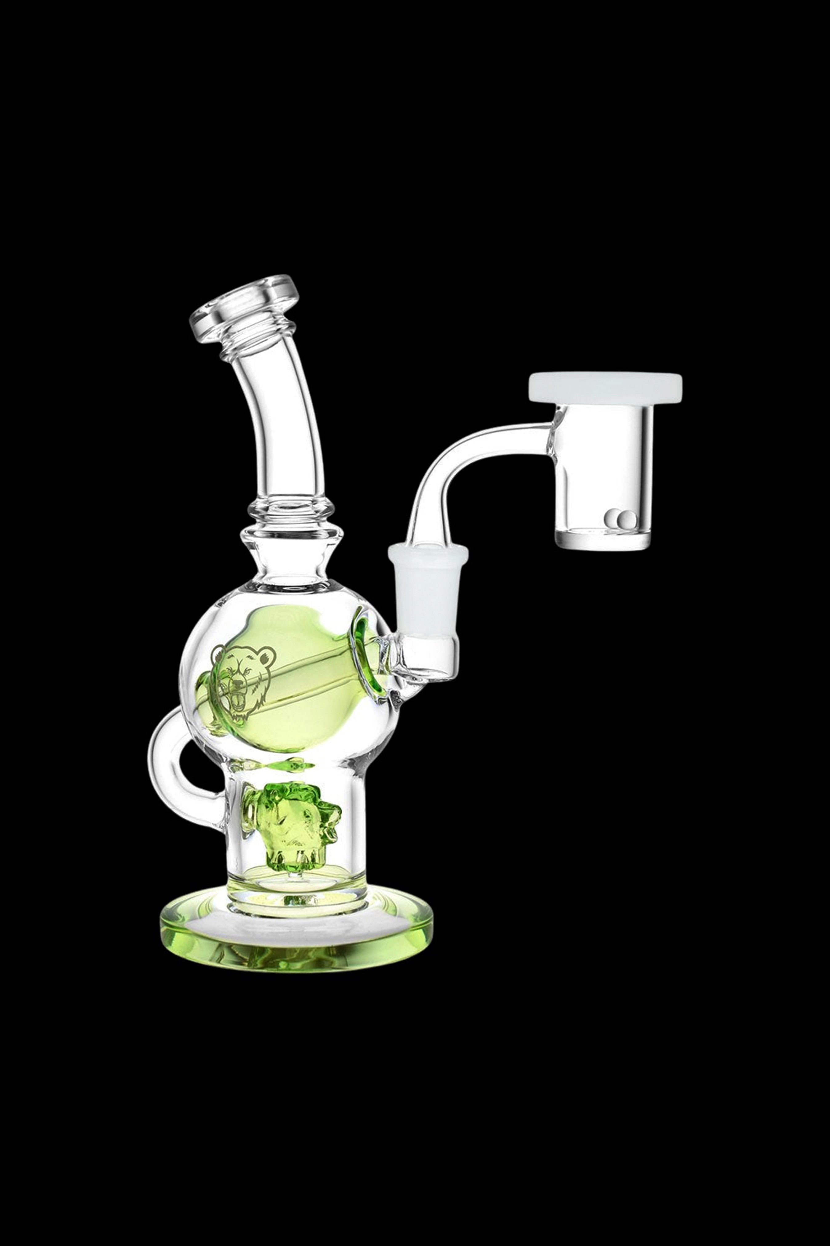 Green glass water pipe (rig) with skull-themed design and accompanying glass nail.