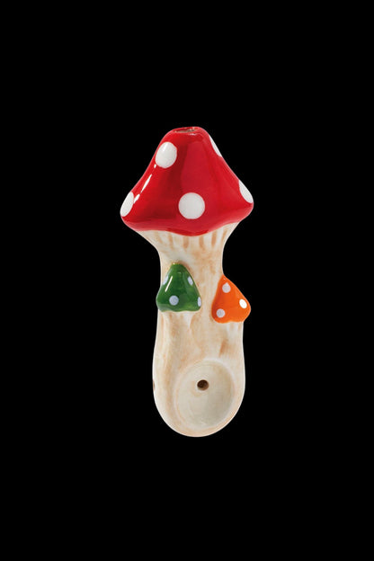 Ceramic mushroom-shaped pipe with red and white spotted cap, against a black background.