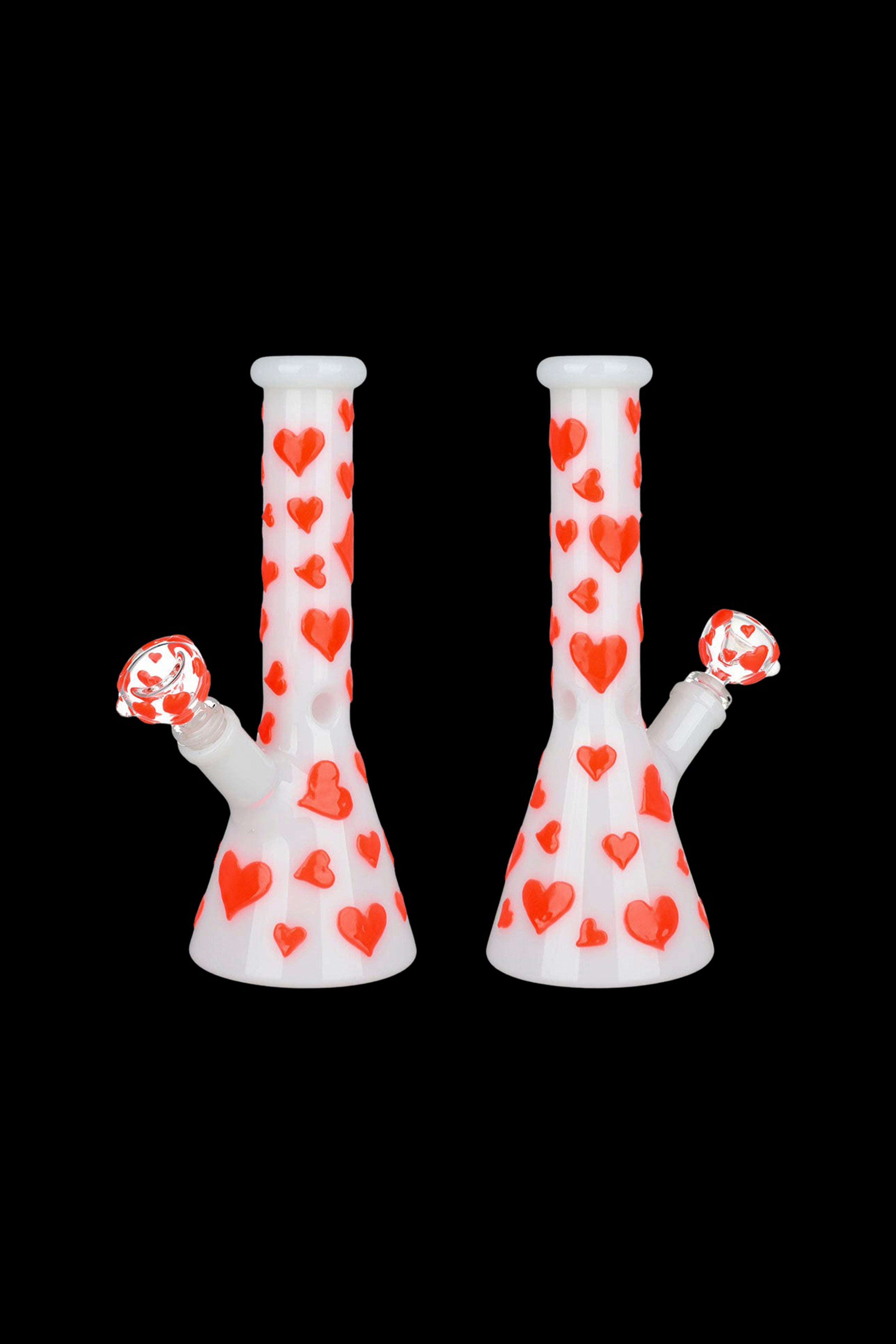 Two white glass bongs decorated with red hearts against a black background.