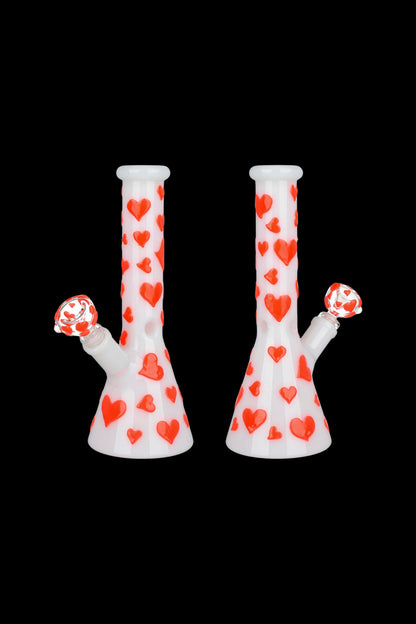 Two white glass bongs decorated with red hearts against a black background.