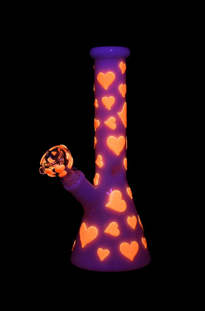 Purple glass bong decorated with orange hearts, isolated on black.