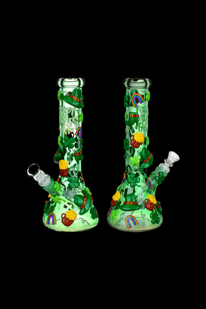 Two green glass bongs decorated with shamrocks, rainbows, and pots of gold against a black background.