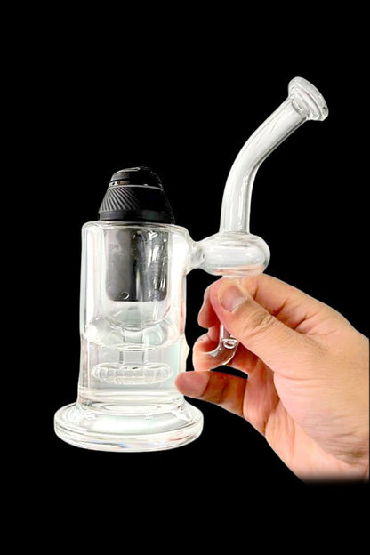 Clear glass rig with a bubbler and mouthpiece held in a hand, against a black background.