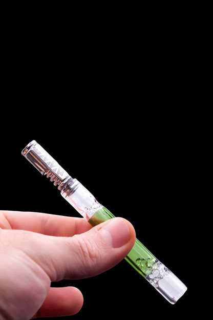 Hand holding a glass cannabis pipe with green and clear accents against a black background.
