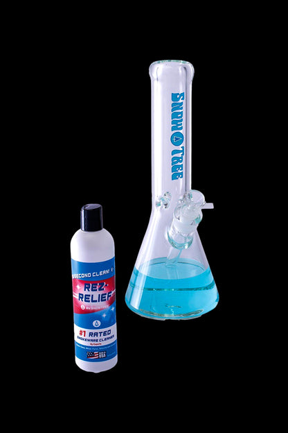 A bottle of Rez Relief glass cleaner positioned next to a clean glass bong on a white surface.