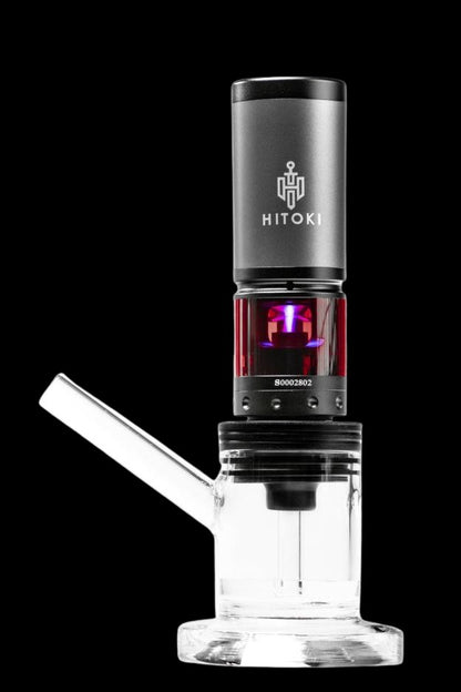White glass rig with a black electronic dab nail (E-nail) displaying a red light, branded with “HITOKI.”