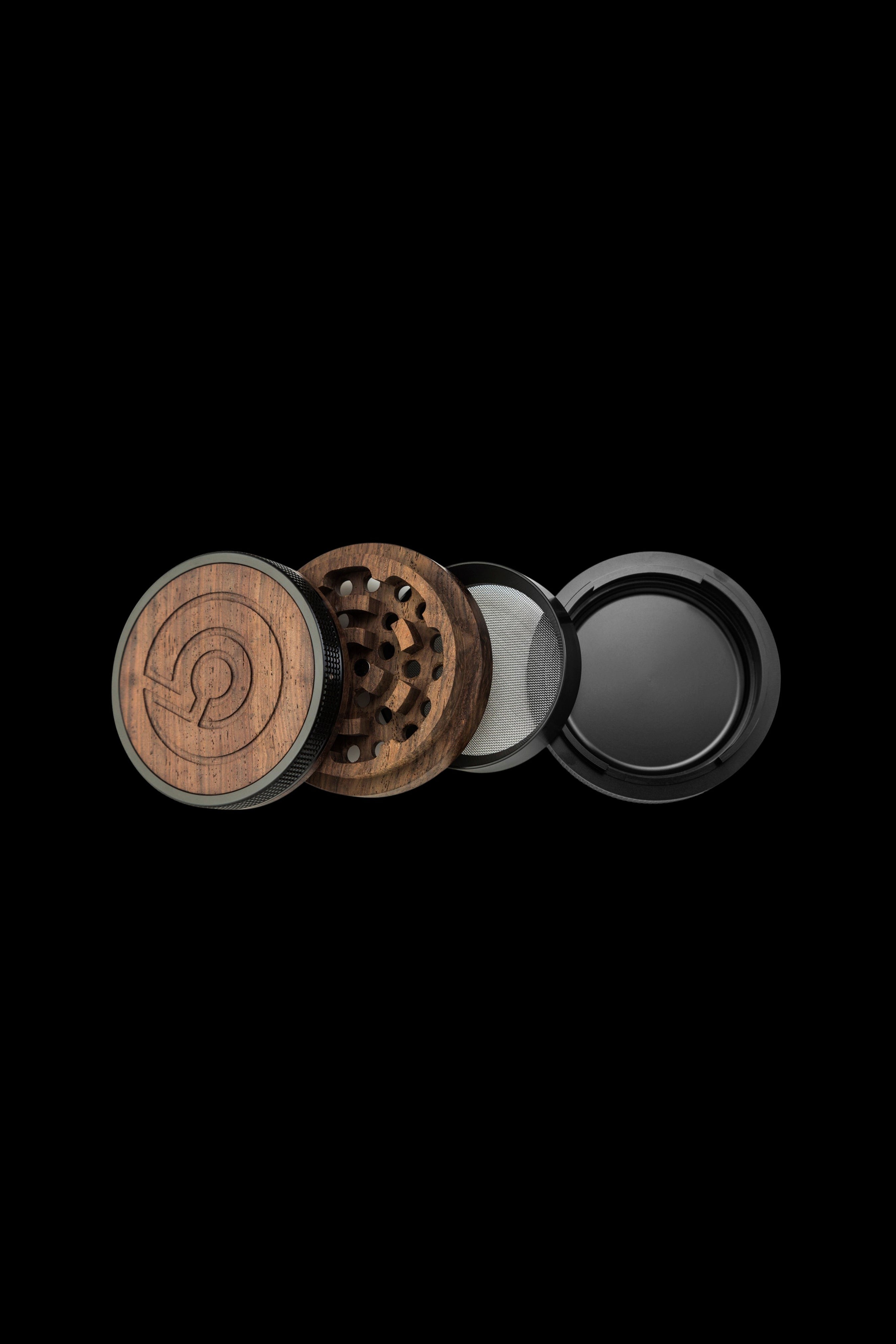Wooden cannabis grinder disassembled, showing individual components against a black background.