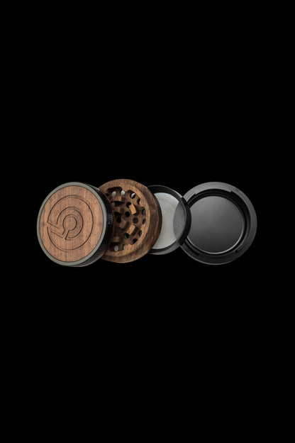 Wooden cannabis grinder disassembled, showing individual components against a black background.