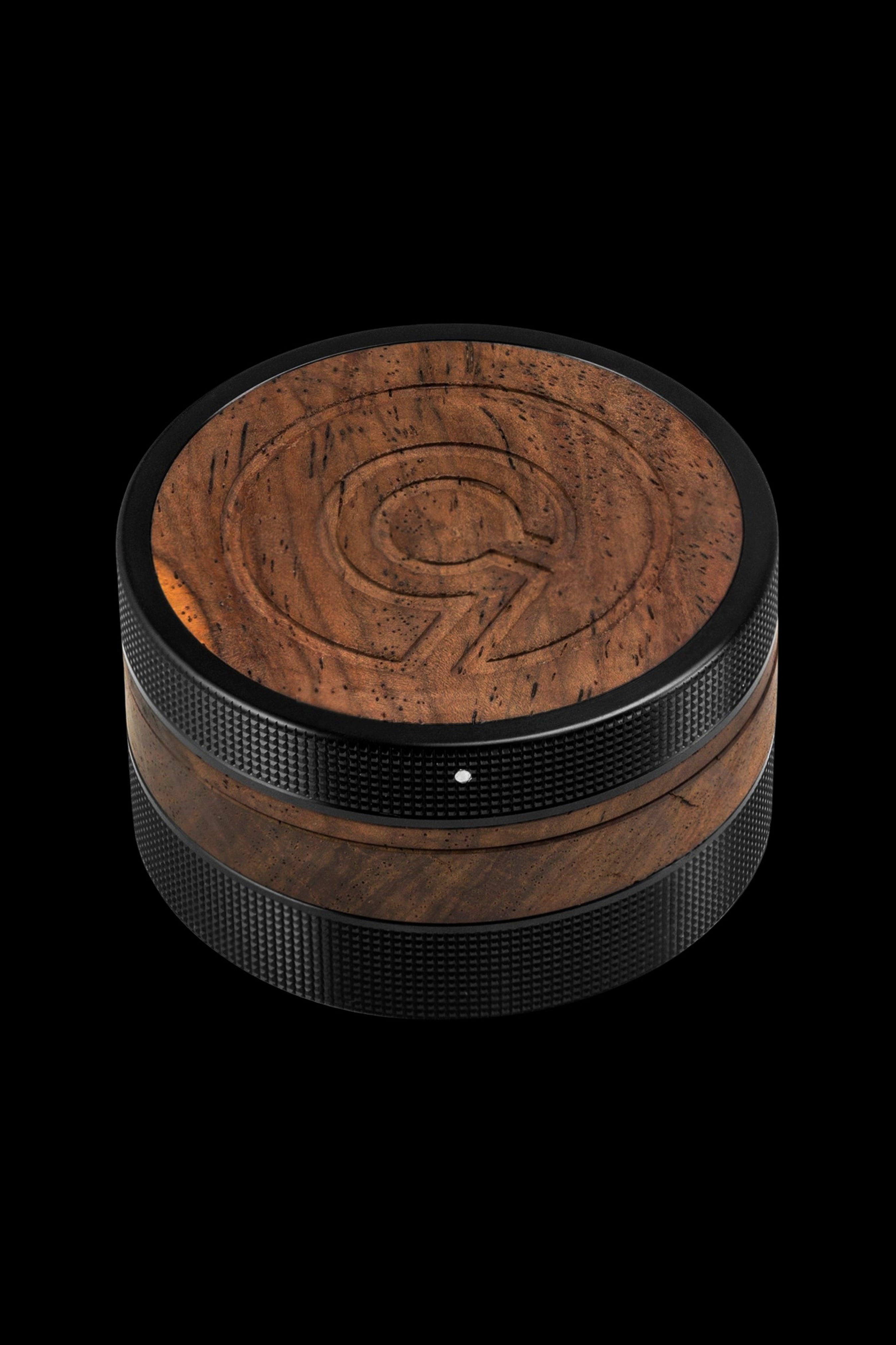 Brown wooden cannabis grinder with textured grip, studio shot on black background.
