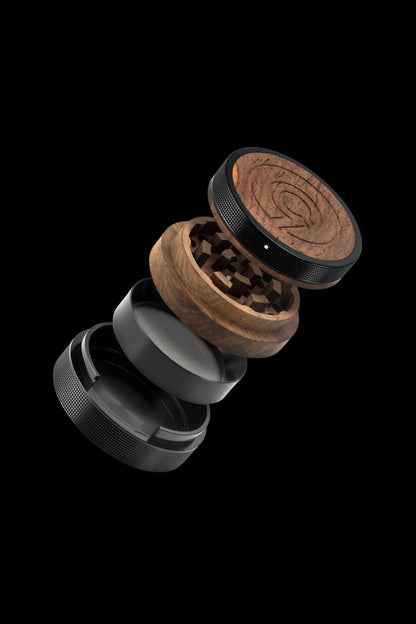 Exploded view of a wooden and metal cannabis grinder against a black background.