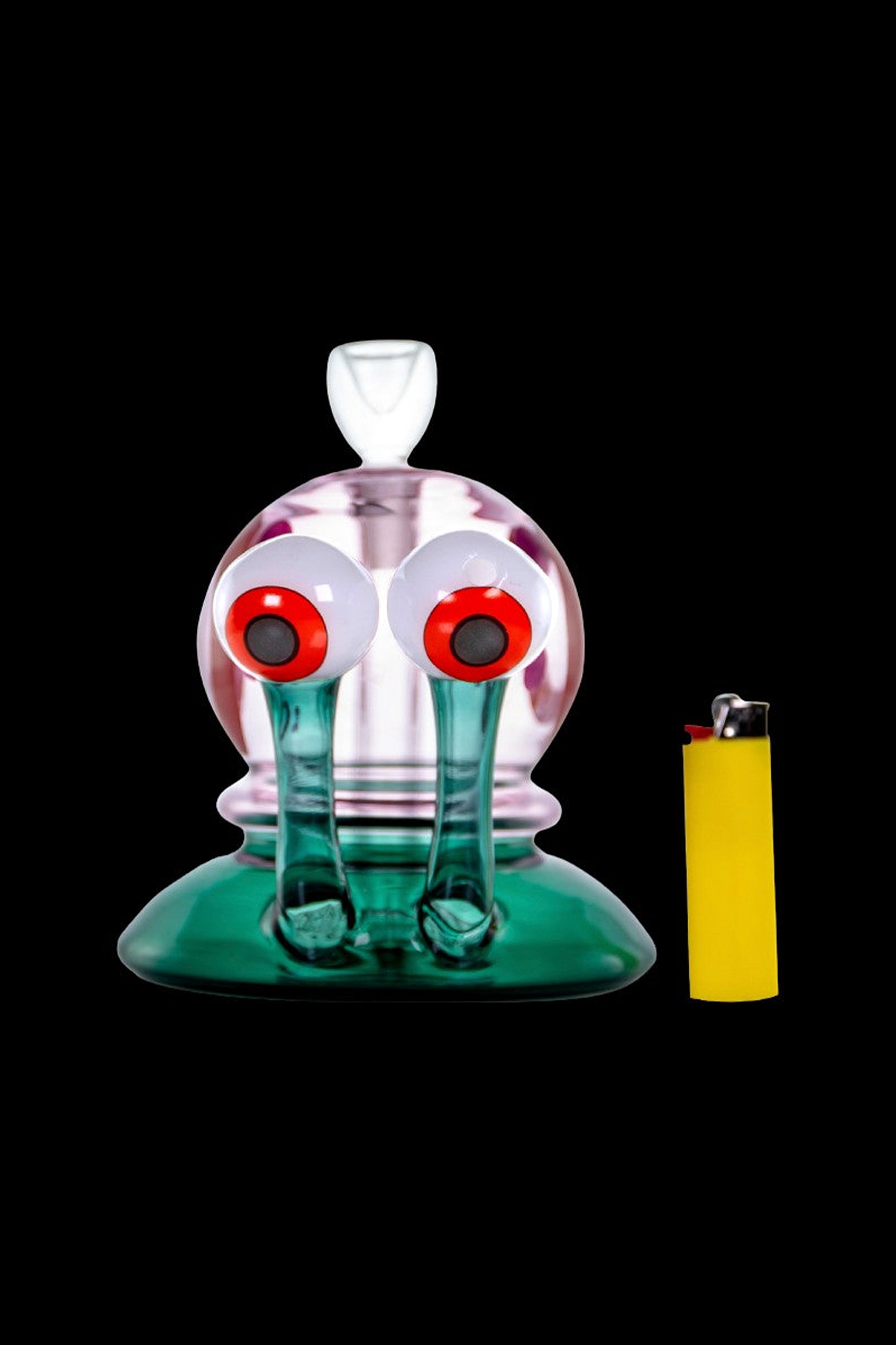 Hand-blown glass rig resembling a crying face with large eyes, alongside a lighter.