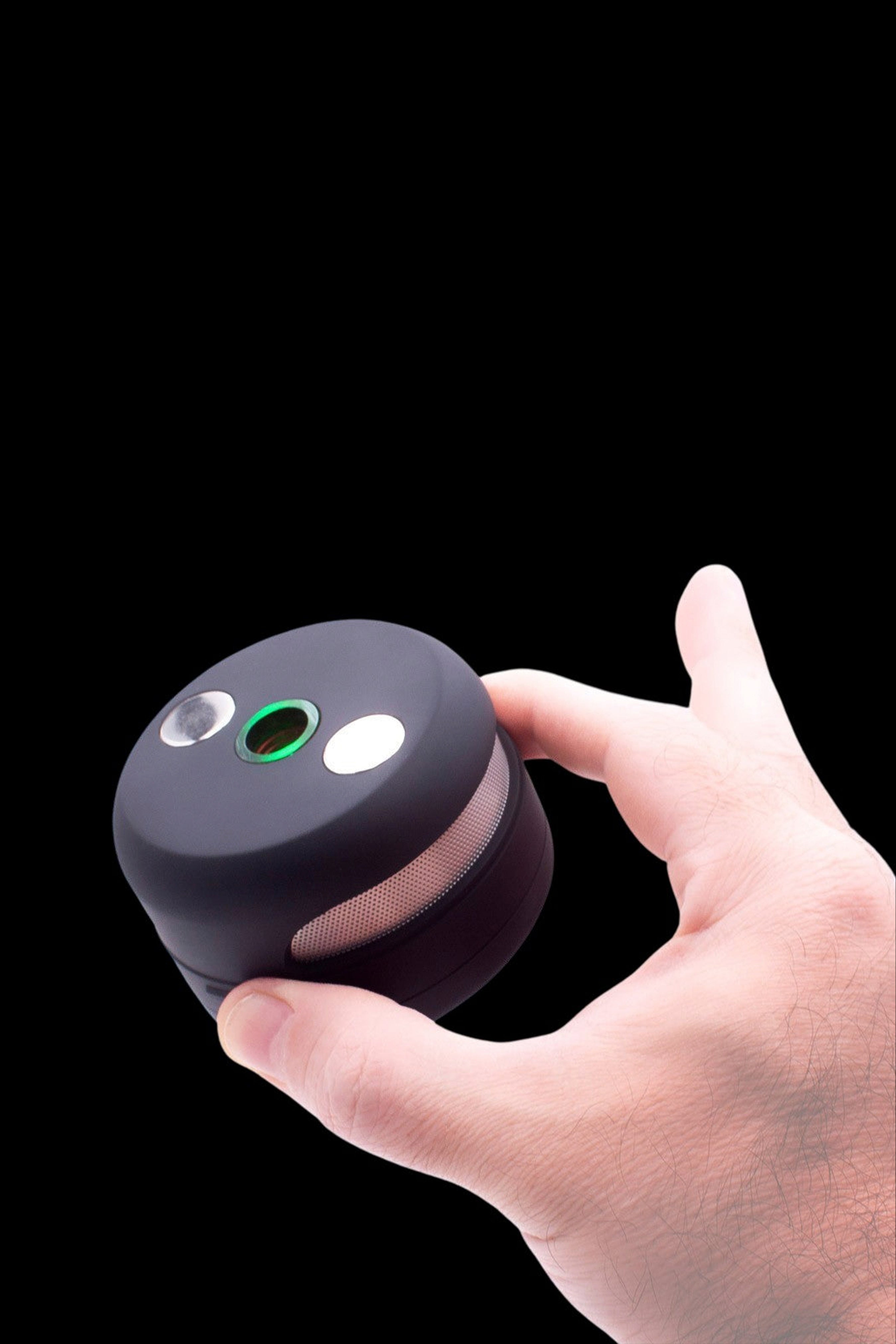 Hand holding a black, spherical cannabis vaporizer with illuminated indicator lights.