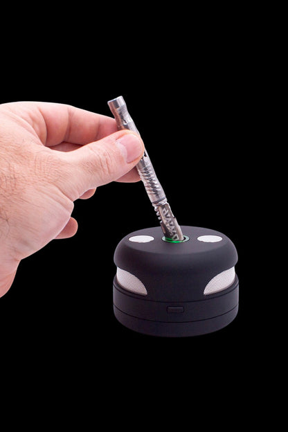 Hand inserting a cannabis oil vape pen into a charging base.