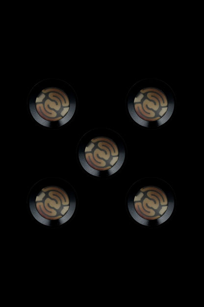 Five metallic cannabis oil cartridge caps with embossed swirling designs against a black background.