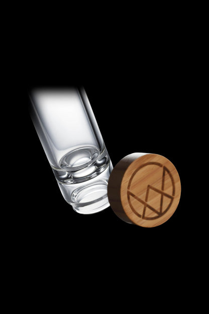 Glass cannabis oil applicator with wooden cap displaying a geometric logo.