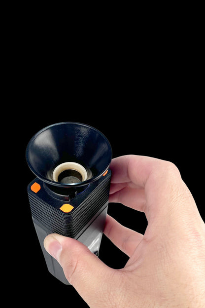 Close-up of a hand holding the Venty Vaporizer Herb Funnel showing its black funnel mouthpiece, inner screen, and textured black body with orange accents.