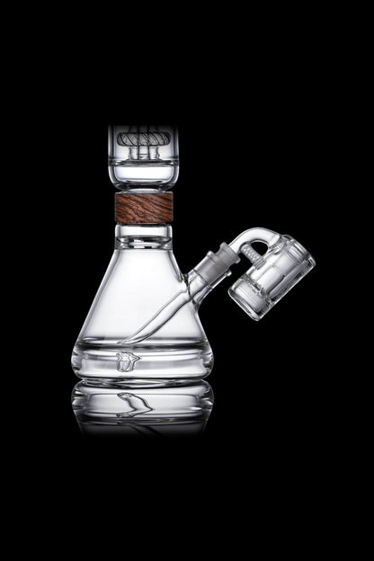 Clear glass water pipe (bong) with wooden accent and connected glass bubbler, displayed on a reflective surface against a black background.