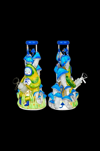 Hand-blown glass water pipe shaped like a whimsical mushroom forest with a smiling face and intricate details, displayed from two angles on a black background.
