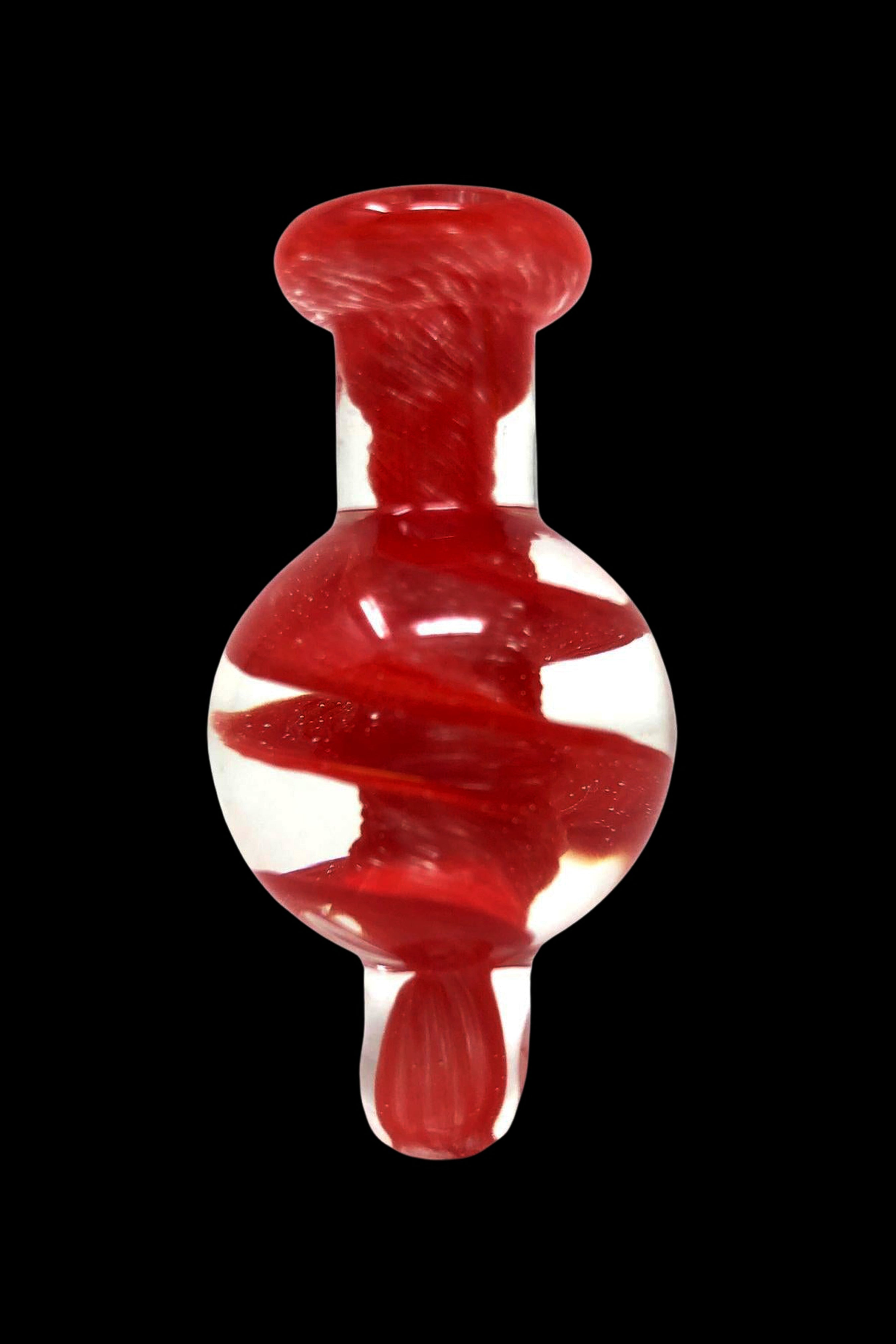 Red and white swirled glass oil rig carb cap against a black background.