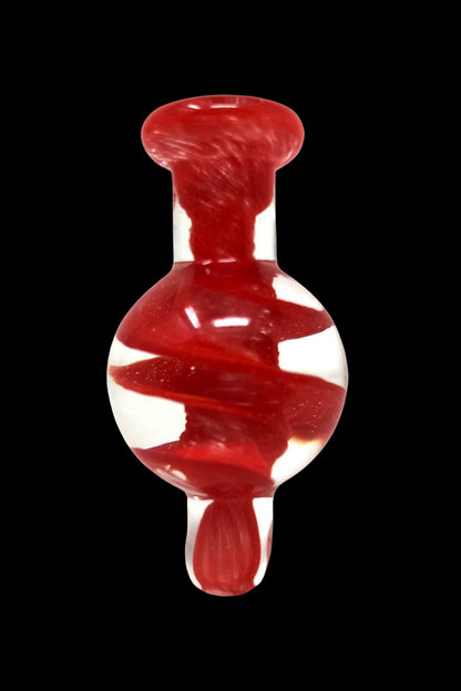 Red and white swirled glass oil rig carb cap against a black background.
