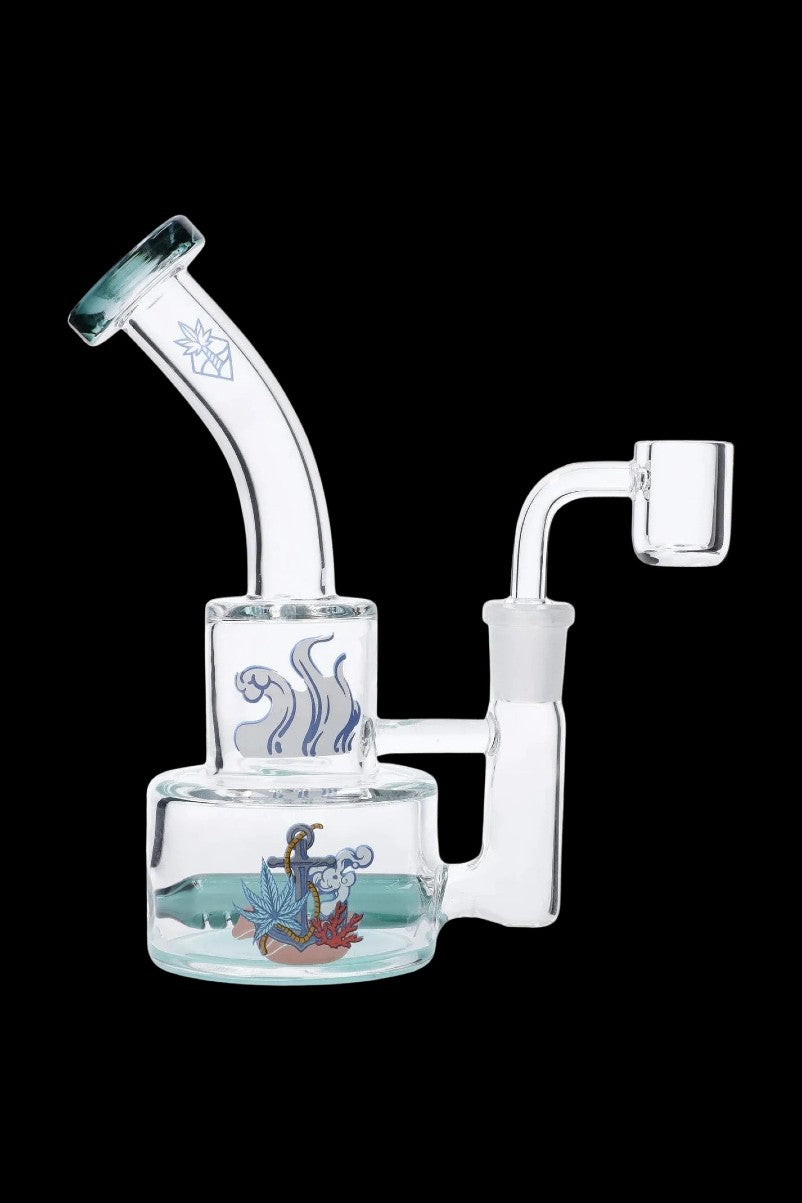 Side view of the teal-accented Cabana Cannabis Co. Ahoy Dab Rig with a curved mouthpiece, clear body, and nautical decal on the base.