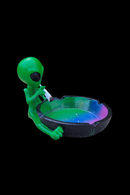 Green alien sculpture holding a glowing ashtray.