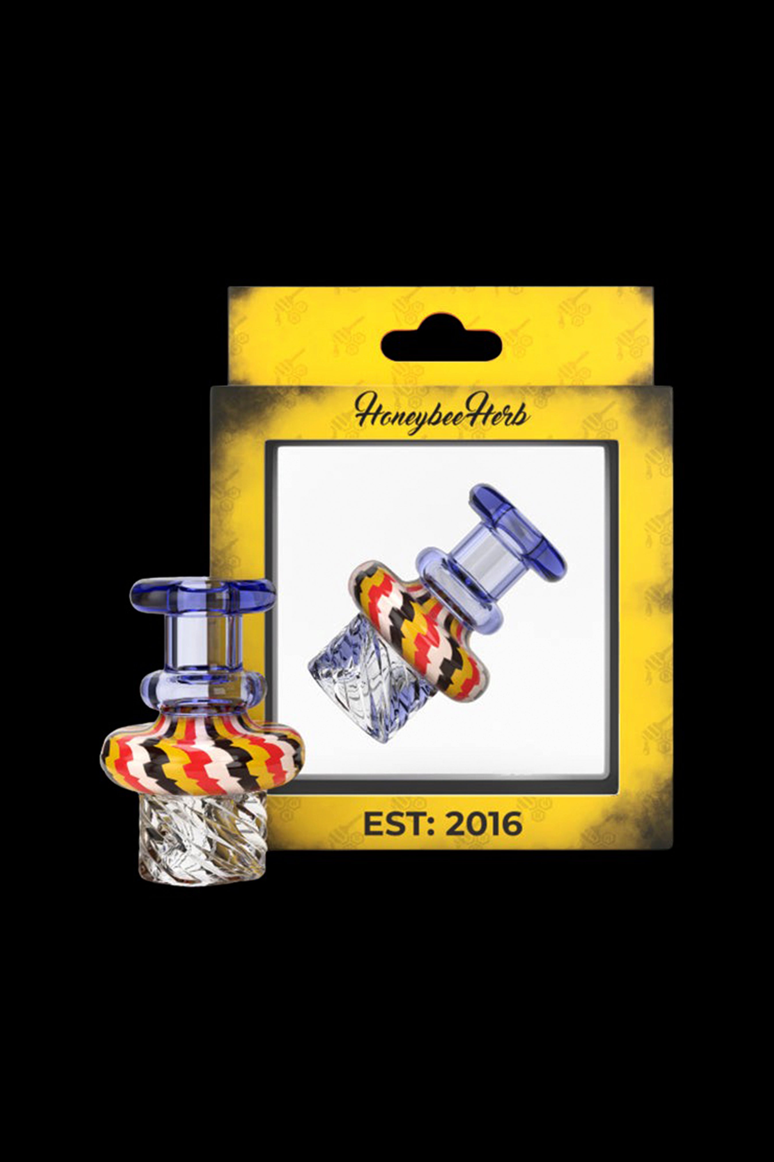 A packaged cannabis concentrate carb cap with colorful glass accents, labeled “Honeybee Herbs EST: 2016.”