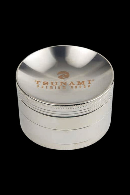 Silver four-piece cannabis grinder with “TSUNAMI PREMIUM VAPOR” engraved on the top.