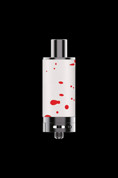 Cannabis oil vaporizer cartridge with a white and red splatter pattern, isolated on a black background.